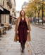Woman in a burgundy wrap dress and camel coat on an autumn city street