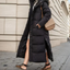 Black maxi puffer coat worn open on a city street