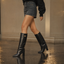 Black knee high boots worn with a mini skirt