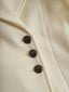 Detail of the faceted dark buttons on the ivory coat