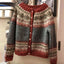 The grey and rust Nordic knit cardigan shown on a stand