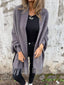 Grey fringed cardigan shown against a stone wall